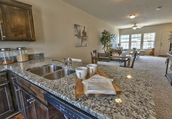 A kitchen with granite countertops and a dining area in the background.
