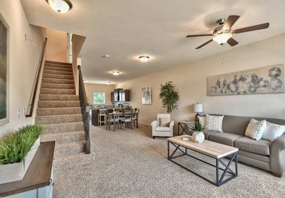 A living room with a staircase and a dining table.