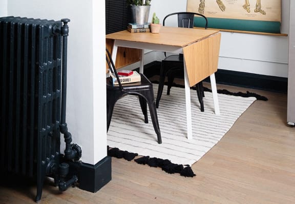 a room with a table and a radiator and a rug on the floor