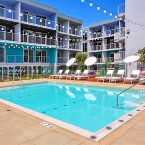 A large swimming pool in front of a multi-story apartment building.at Prizma, Los Angeles, CA 90038