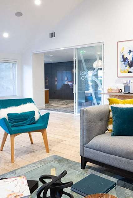 A living room with a grey couch, a blue chair and a small table at Bella Vista at Hilltop Apartments, Richmond, CA, 94806