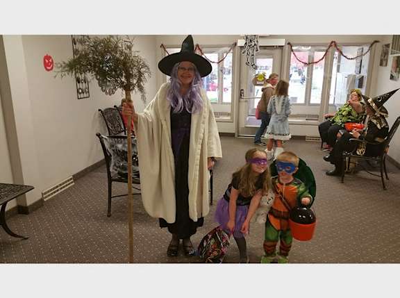 a woman in a witch costume standing next to two children in halloween costumes