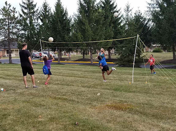 A group of people playing volleyball in a park.