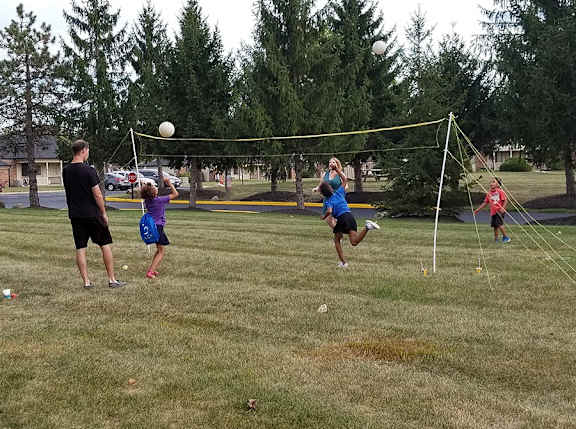 A group of people playing volleyball in a park.