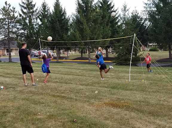 A group of people playing volleyball in a park.