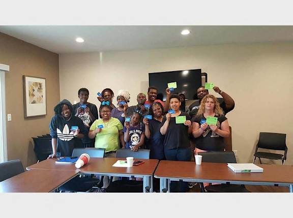A group of people holding up green cards in a room.