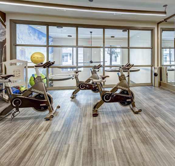 A room with exercise bikes and a TV screen at Arise Riverside Apartments, Austin, TX, 78741