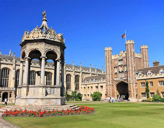 A large building with a tower and a flag on top, with a fountain in front of it. at Origins Apartments, Cambridge