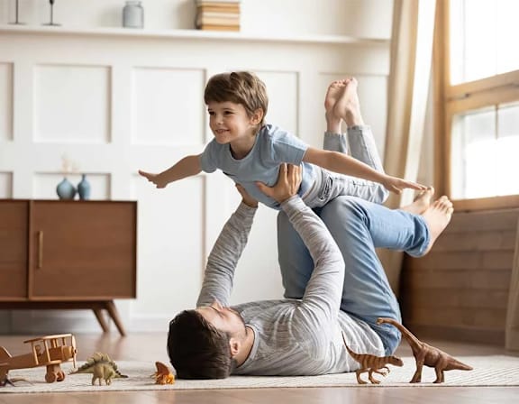 a father playing with his child on top of him on the floor at UnionView Apartments, Dartford, KENT