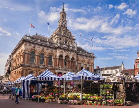 a city with a flower market in front of a building