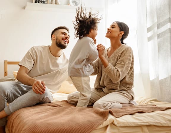a man and woman sitting on a bed with their child