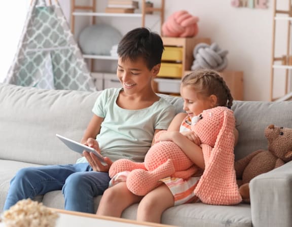 a father and daughter sitting on a couch with a tablet