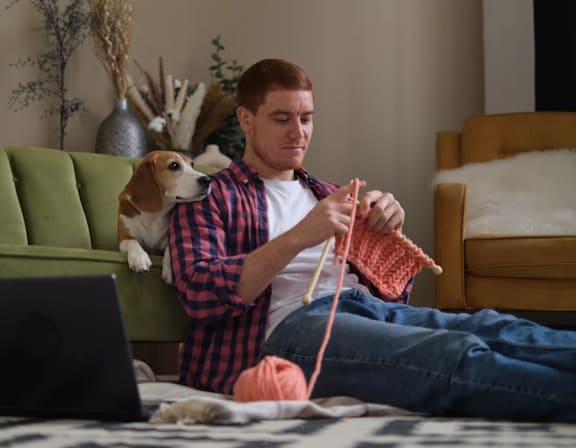 a man is sitting on the floor with a dog and a laptop