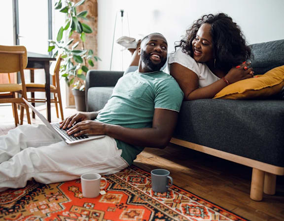 a man and woman laying on a couch with a laptop