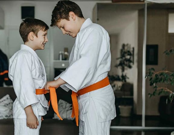 Two boys wearing white judo uniforms with orange belts standing in a room at UnionView Apartments, Dartford, KENT DA2 6GZ