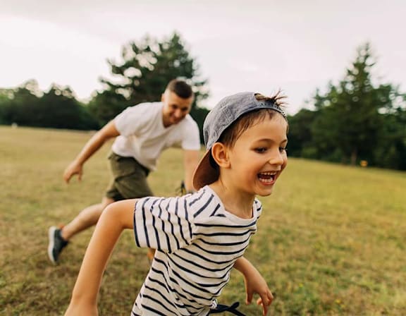a man and a child running in a field at UnionView Apartments, Dartford, KENT DA2 6GZ