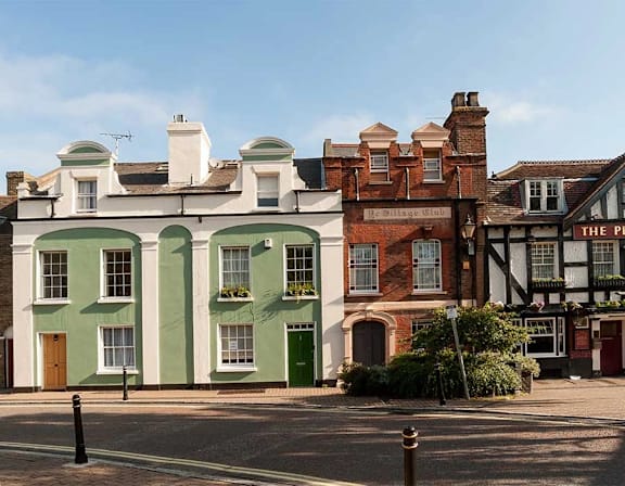 A street view of a green building with a brown door and windows at UnionView Apartments, Dartford, KENT