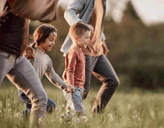 A group of people, including children, are playing in a grassy field. at Origins Apartments, Cambridge