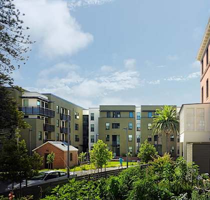 A row of modern apartment buildings with green trees in the foreground.