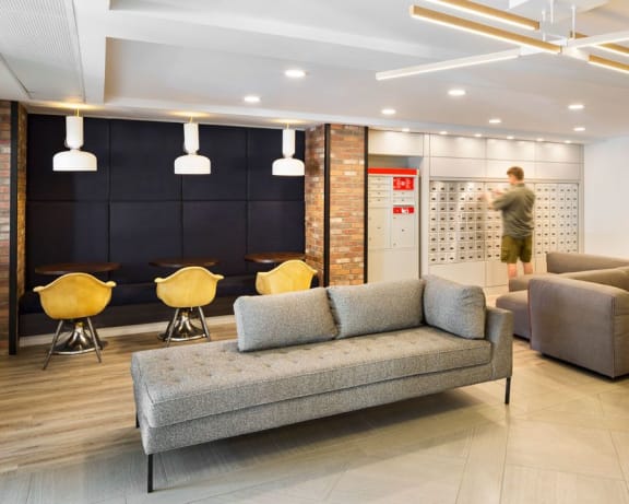 lobby with seating areas and a man checking his mail at the mailboxes.