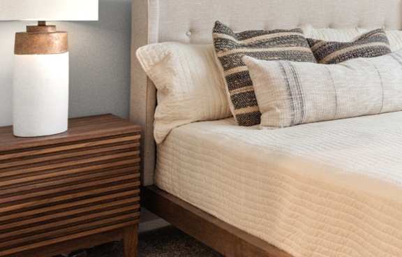 a bed with pillows and a night stand with a lamp