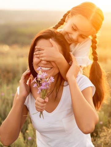 Mom and daughter in field with floweres