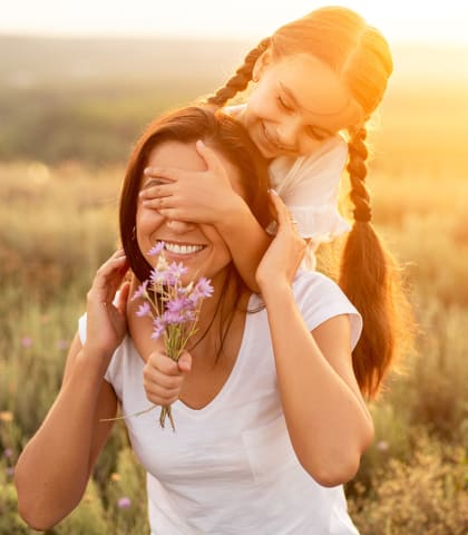 Mom and daughter in field with floweres