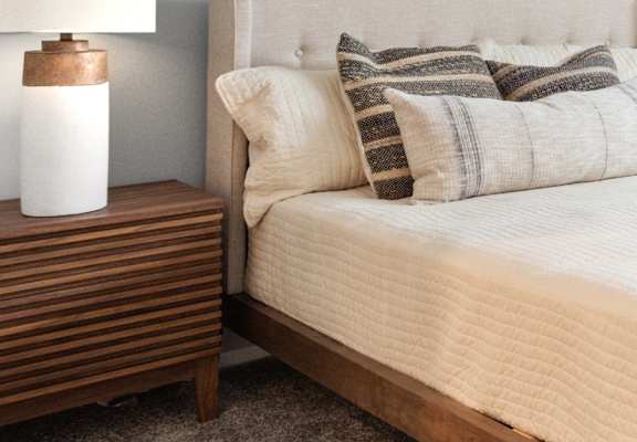 a bed with pillows and a night stand with a lamp