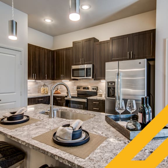 A modern kitchen with a marble countertop and stainless steel appliances.