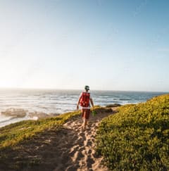 a man walking on a sandy path near the ocean