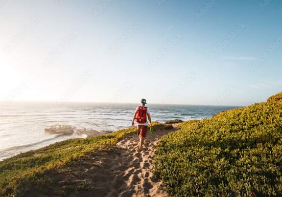 a man walking on a sandy path near the ocean
