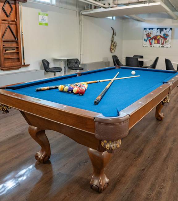 A pool table with a green felt cloth and white cue sticks.