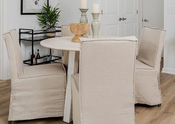 A dining room with a table, chairs and a plant.