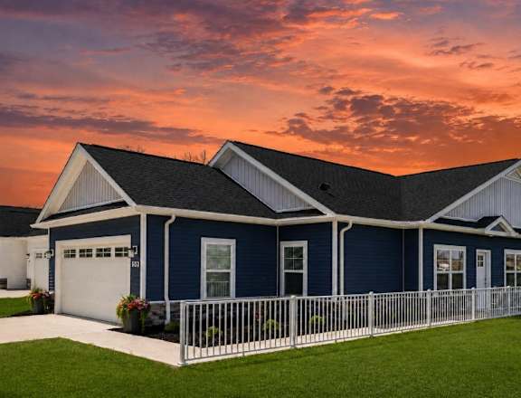 A blue house with a white fence in front of it.