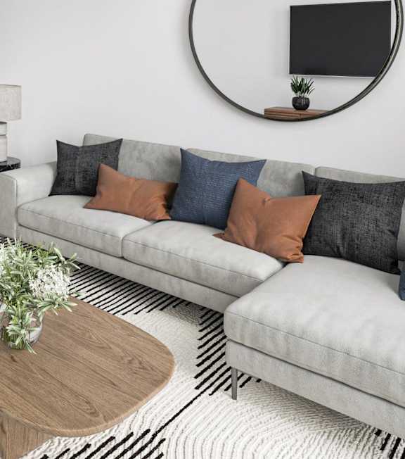 A grey couch with pillows and a wooden coffee table in front of it.