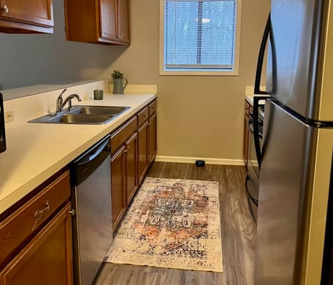 a kitchen with wooden cabinets and a rug on the floor