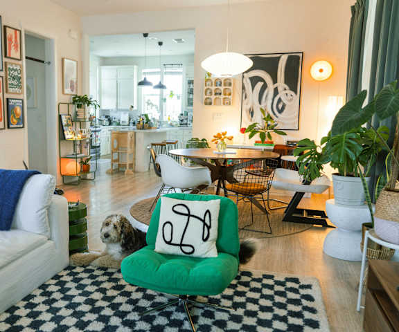 A dog is sitting on a green chair in a living room.