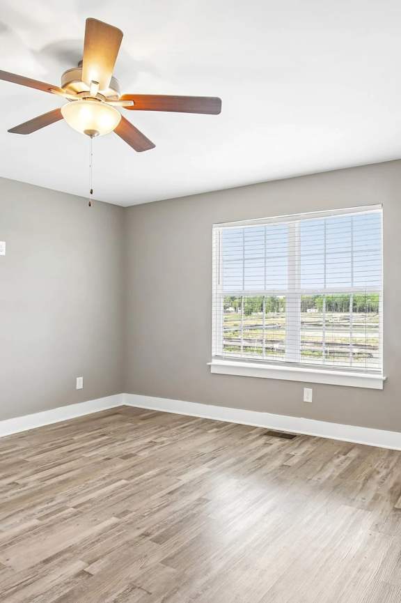 A room with a ceiling fan and a window with blinds.