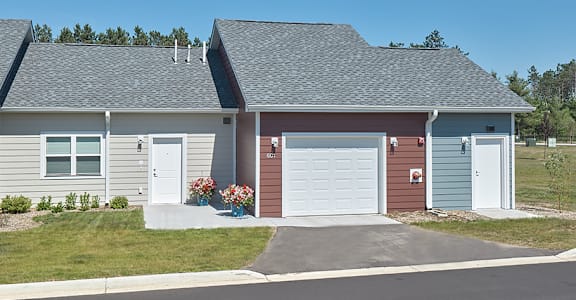 A house with a grey roof and a red garage door.