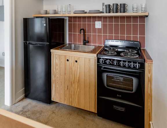 a small kitchen with a black stove and refrigerator and a sink