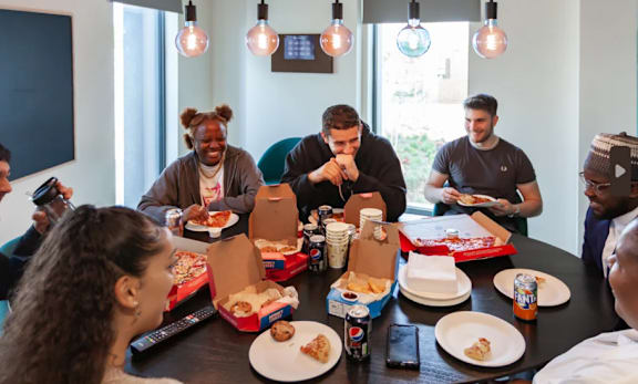 a group of people sitting around a table eating pizza