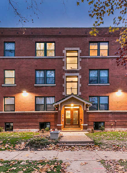 A red brick building with a lit entrance and windows.
