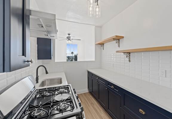 A modern kitchen with a black stove top oven and dark cabinets.