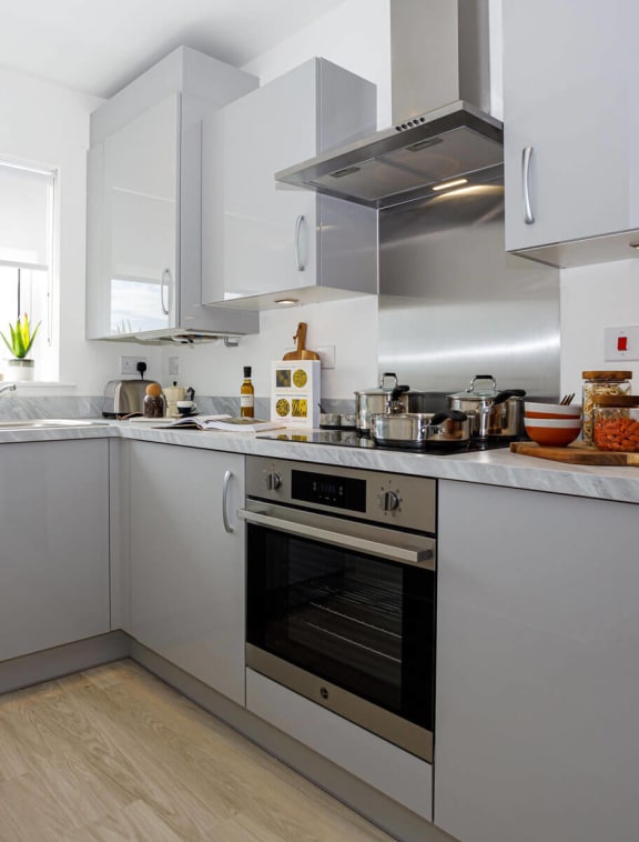 a small kitchen with white cabinets and a wooden floor
