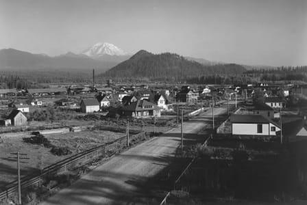 a black and white photo of a town with a mountain in the background