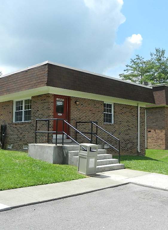 A small building with a red door and a handicap sign in front.