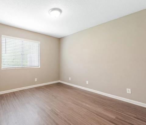 an empty living room with wood floors and a window