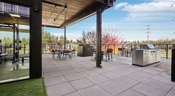 a patio with a grill and a table with chairs at AVIVA apartments in Gresham Oregon