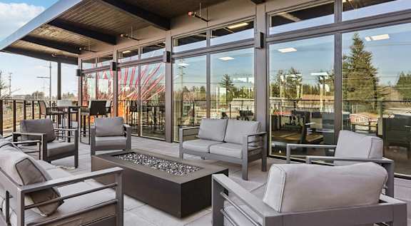 a lounge area with couches and chairs in front of glass doors at AVIVA apartments in Gresham Oregon