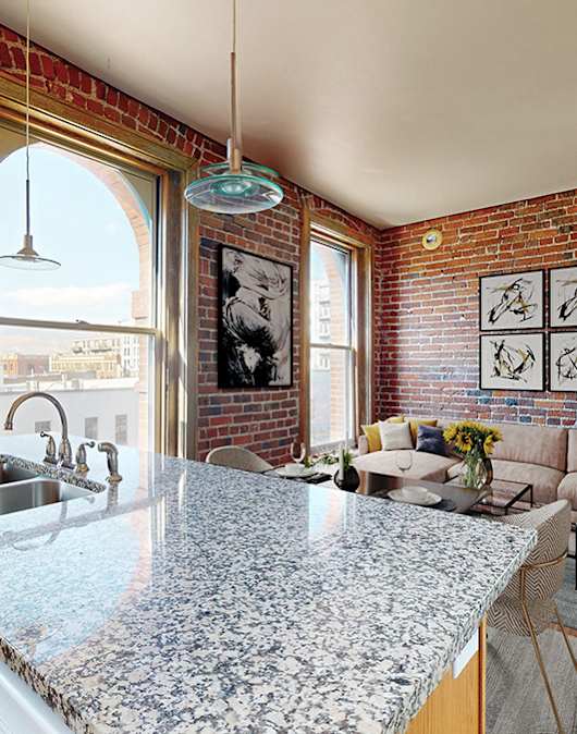 A kitchen with a granite countertop and a brick wall.